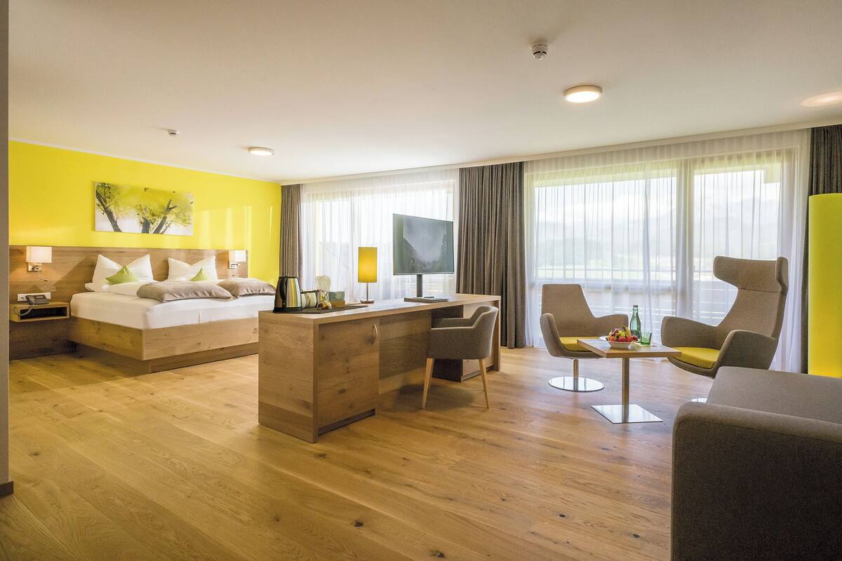 A hotel room with a bed, desk, and two chairs.