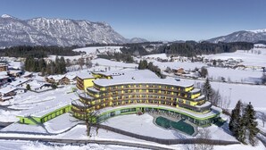 A multi-story hotel with a curved facade, a swimming pool, and snow-covered surroundings. - DAS SIEBEN ****s - Adults Only (Bad Haering)