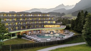 A hotel with a pool, outdoor seating, and a view of mountains. - DAS SIEBEN ****s - Adults Only (Bad Haering)