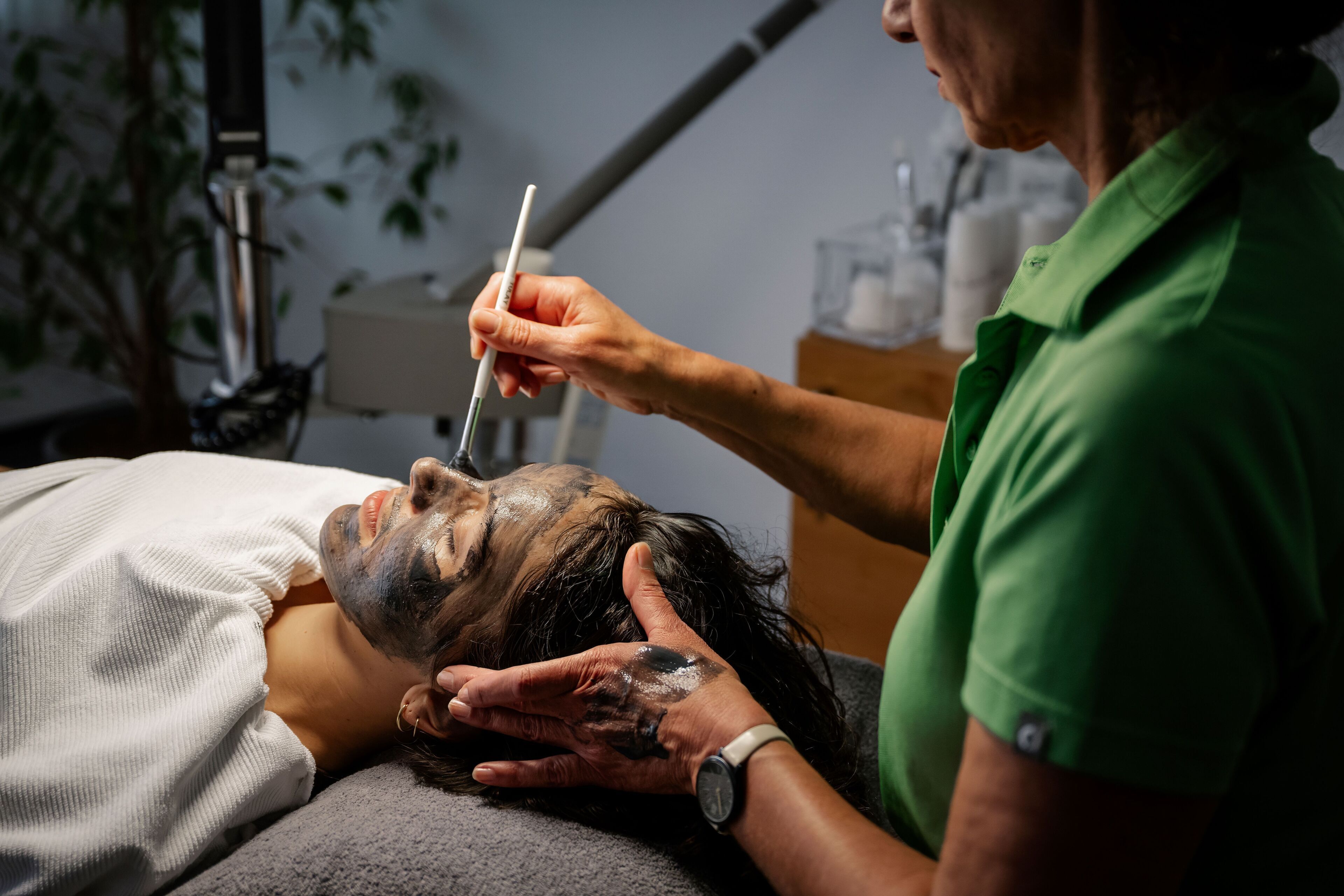 A person lying down with a face mask on, being attended to by another person.