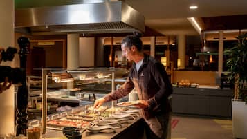 A buffet area with a variety of food items, a buffet counter, and a person serving.