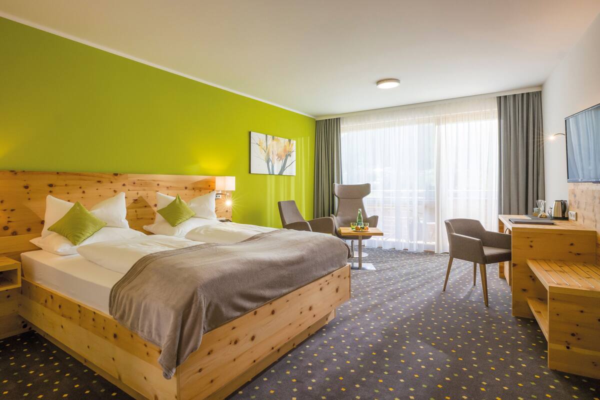 A hotel room with a large bed, two bedside tables, a desk, and a chair.