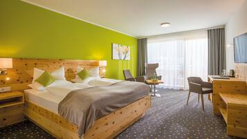 A hotel room with a large bed, two bedside tables, a desk, and a chair.