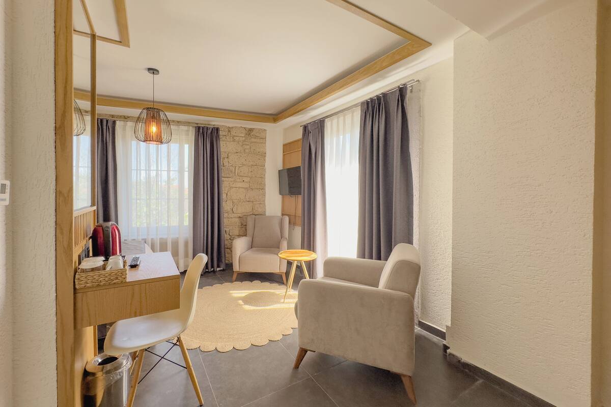 A modern living room with a stone wall, a television, a sofa, a chair, a small round table, and a coffee table.