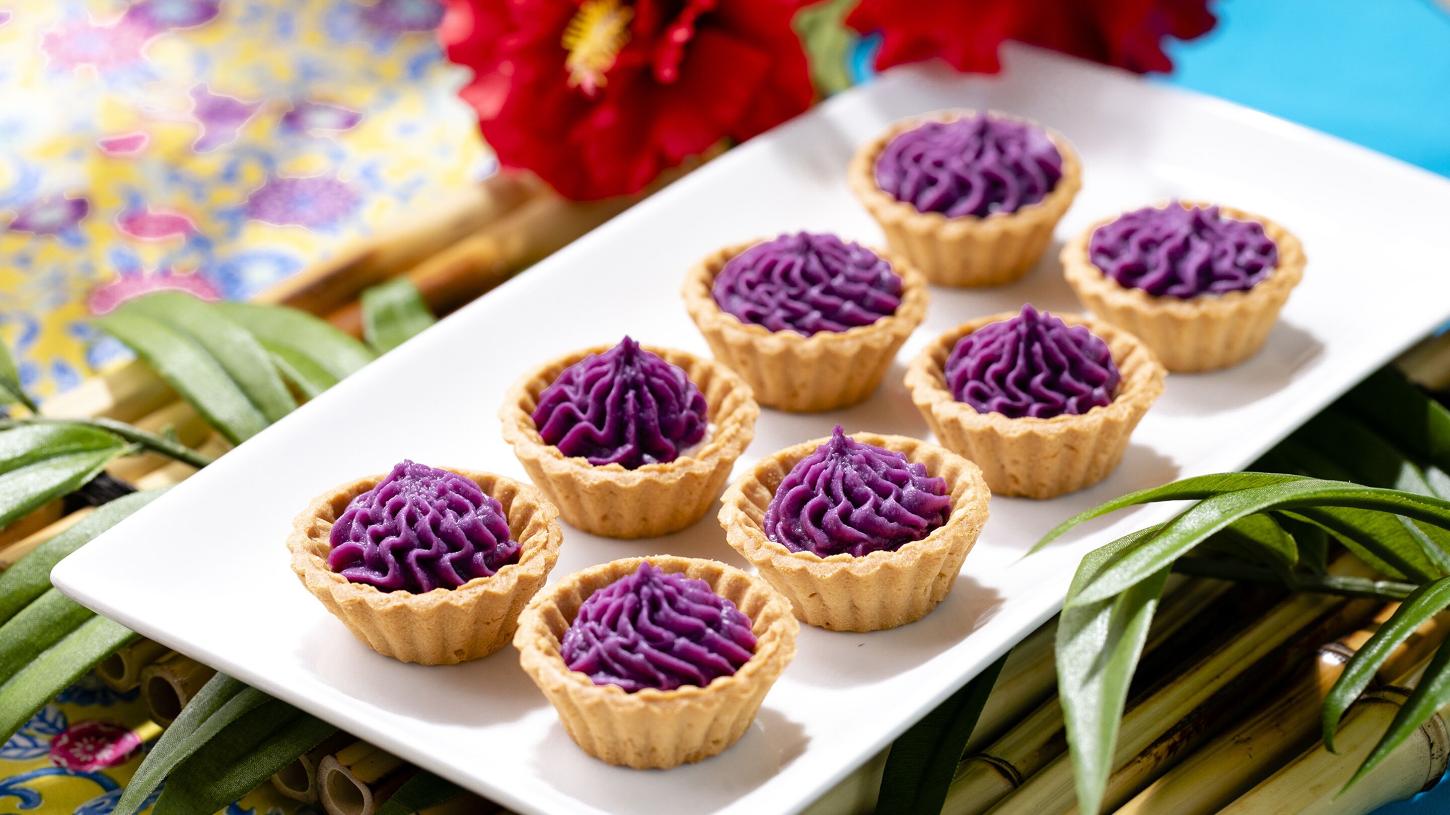 A white rectangular plate with eight purple-colored tartlets arranged in two rows.