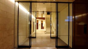 Un vestíbulo de hotel moderno con entrada de vidrio, una escalera y una zona de recepción.