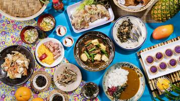 A variety of dishes including rice, vegetables, and meat, arranged on a colorful tablecloth.