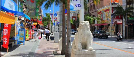 Una calle urbana concurrida con una estatua de león de piedra en el centro.