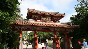 Une porte chinoise traditionnelle, agrémentée d’une inscription, entourée de verdure.