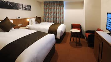 Une chambre d’hôtel avec deux lits, une petite table ronde, un téléviseur et une chaise rouge.