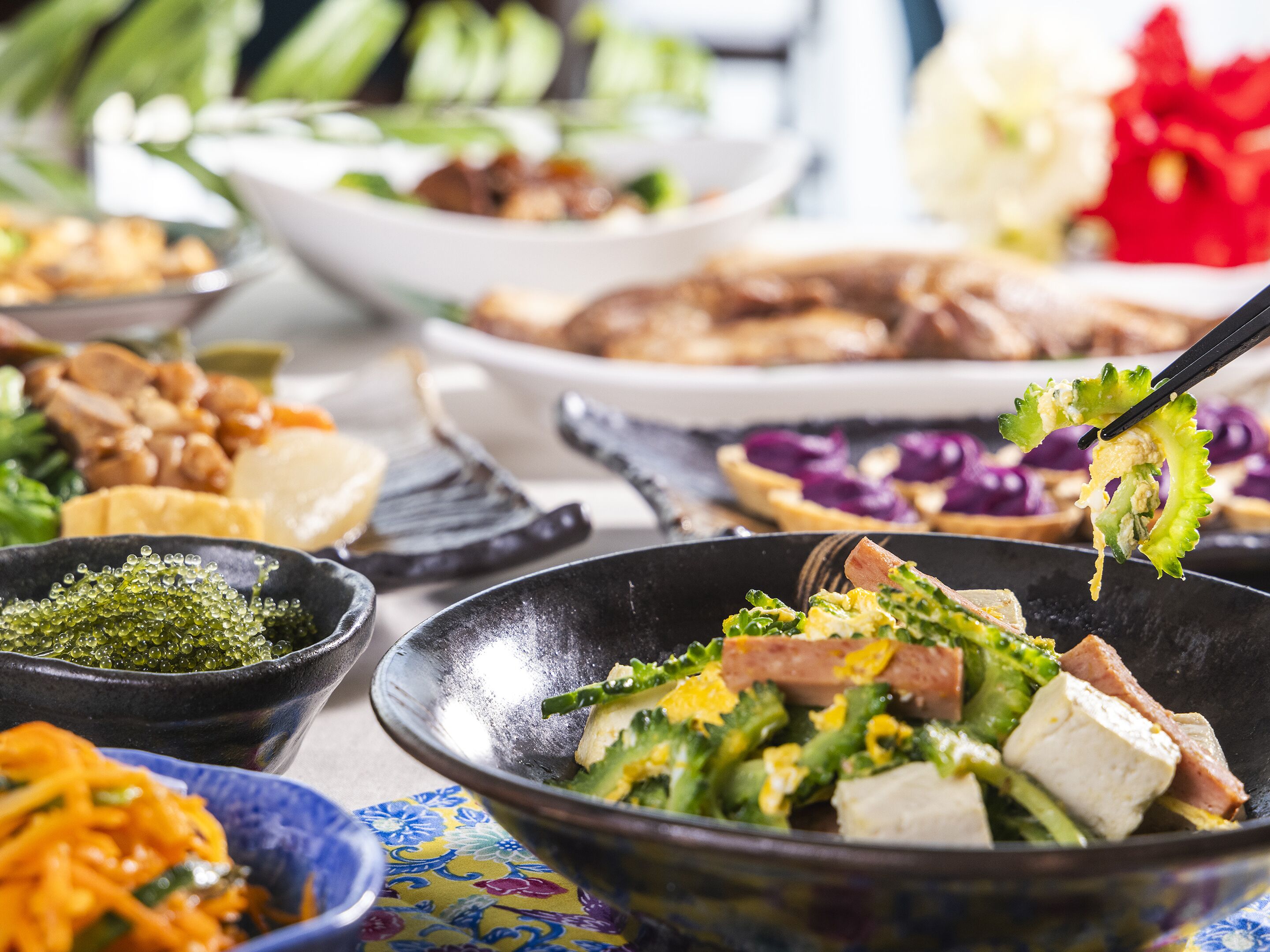 Variedad de platos en una mesa, incluyendo un tazón de ensalada con brócoli y tofu, un tazón de salsa verde y otros alimentos.