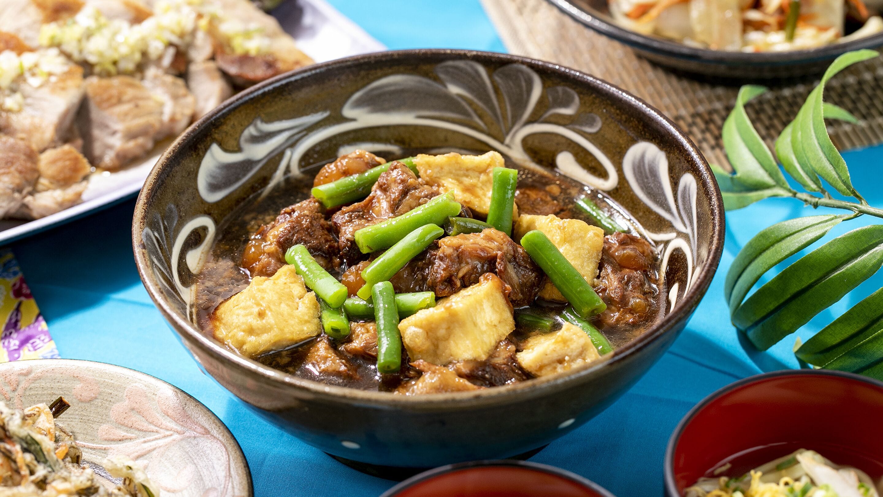 Un plato de estofado con tofu y judías verdes, servido en un plato decorativo.