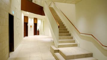 Un moderno vestíbulo de hotel con suelo de mármol, una escalera de madera y un nivel entre pisos.