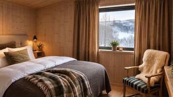 A cozy room with a bed, a chair, a window with a view of snow-covered trees, and a lamp.