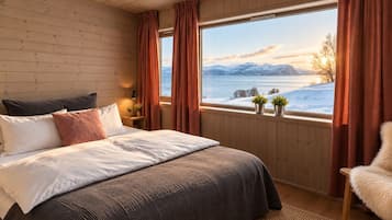 A bedroom with a large window, wooden walls, a bed with multiple pillows, a nightstand, and a chair.