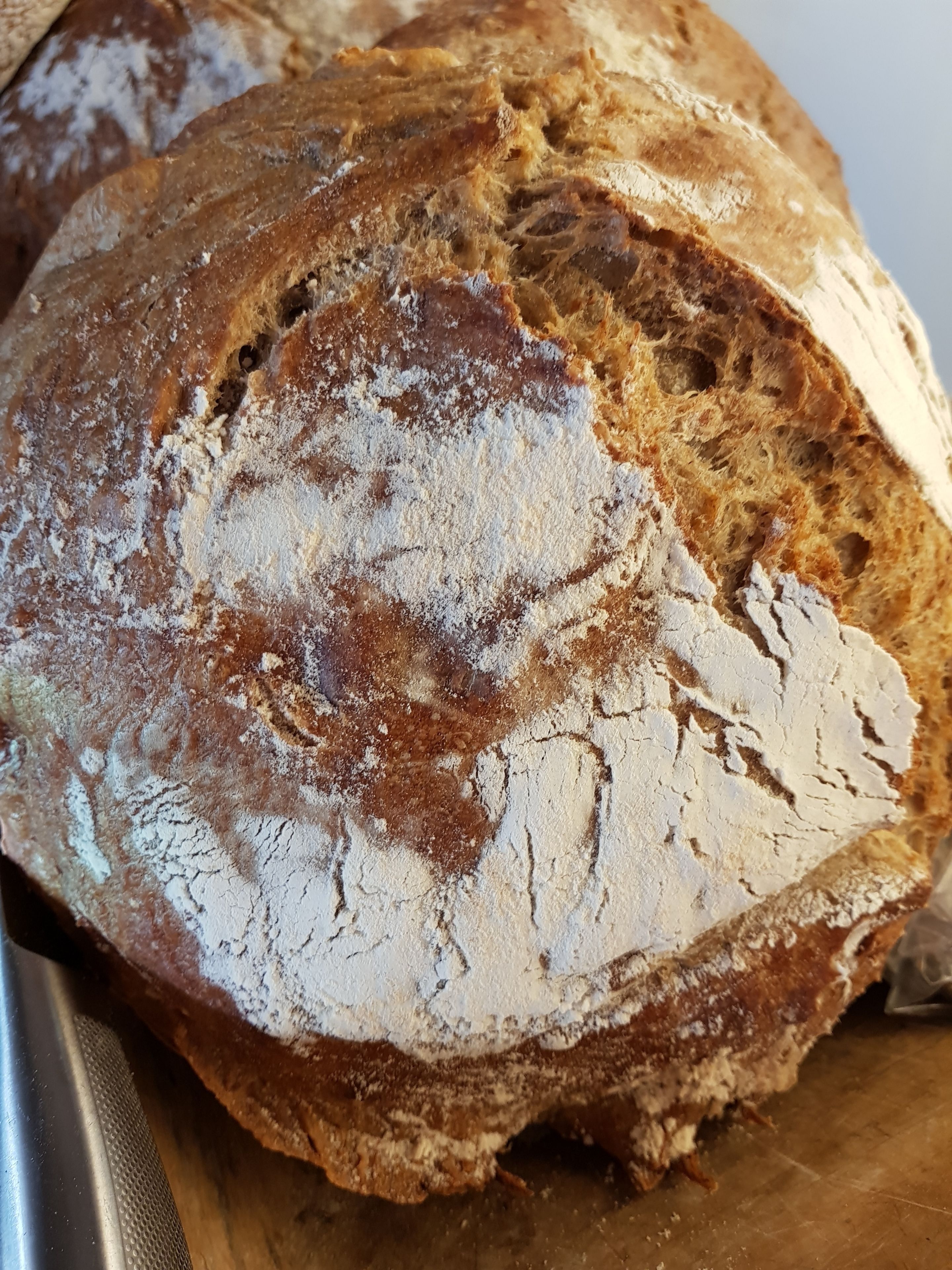 A loaf of bread with a dusting of flour on a cutting board.