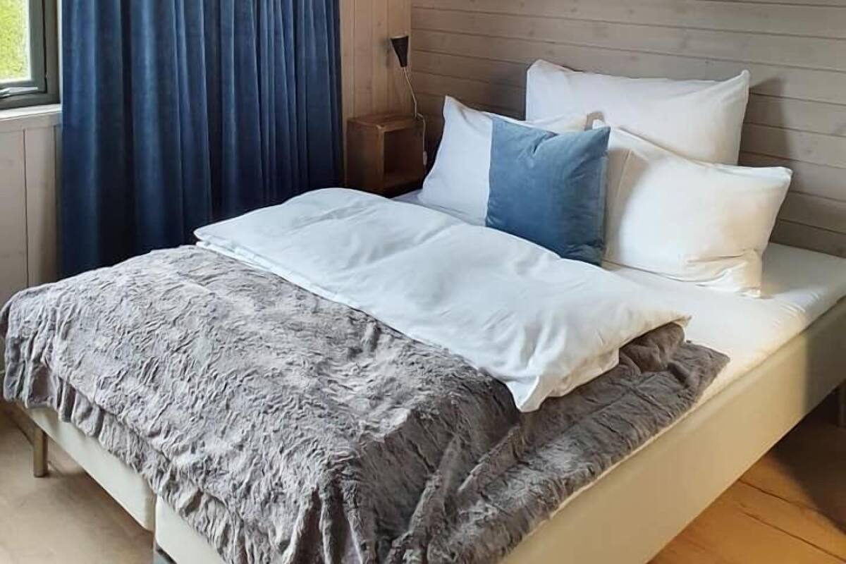 Ein Schlafzimmer mit einem Bett, einem Fenster mit Vorhängen und einer Holzwand.