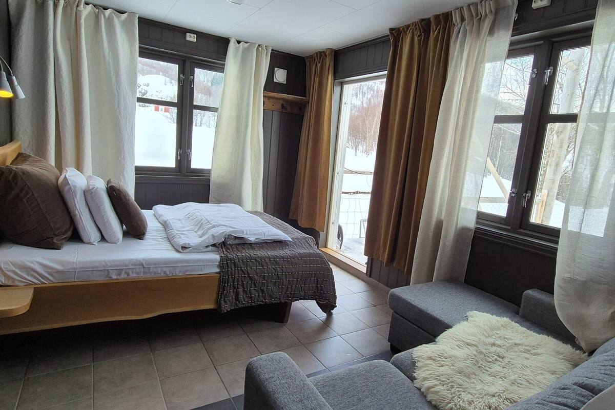 Ein Zimmer mit einem Bett, einem Sofa und einem Fenster mit Vorhängen.