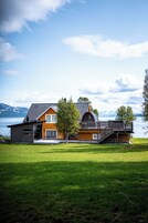 A modern house with a large deck, a garage, and a view of a lake.