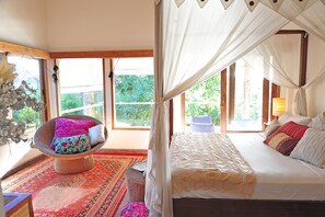 Un dormitorio con una cama, una silla y un ventanal amplio.