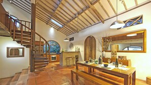 Una cocina amplia con una escalera de madera, un comedor con mesa de madera y un gran ventanal con vistas al jardín.