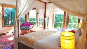 Un dormitorio con cama con dosel, ventanas amplias y vistas al verdor.