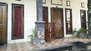 Fachada d'edifici amb diverses portes, una columna de pedra i una estàtua.