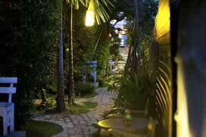 Um caminho arborizado com bancos, que leva a um edifício com entrada visível.
