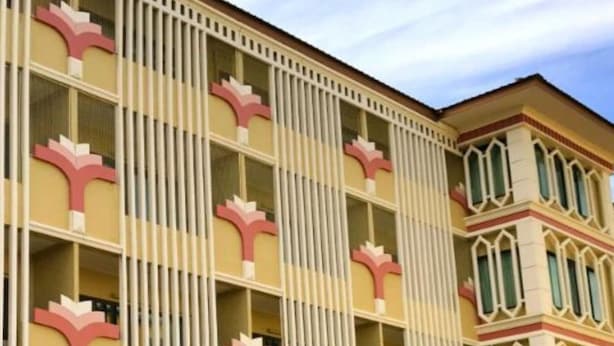 A multi-story hotel with a distinctive facade featuring vertical white columns and pink floral motifs. - PoonSook Resident Hotel (Phitsanulok)