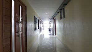 A long, narrow hallway with wooden doors on one side and windows on the other. - PoonSook Resident Hotel (Phitsanulok)