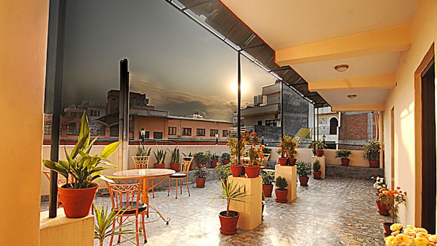 Une terrasse sur le toit, avec une table et des chaises, entourée de plantes et de fleurs en pot.