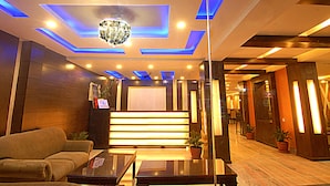 Un hall d’hôtel moderne avec un canapé, une table basse, un lustre et un escalier.