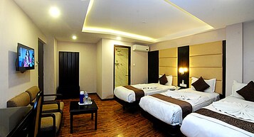A hotel room with two beds, a TV, a desk, and a chair.
