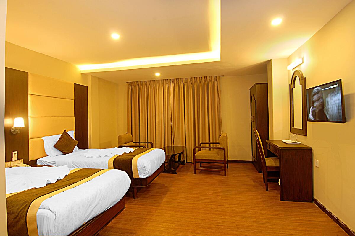 A hotel room with two beds, a desk, a chair, a television, and a curtain.