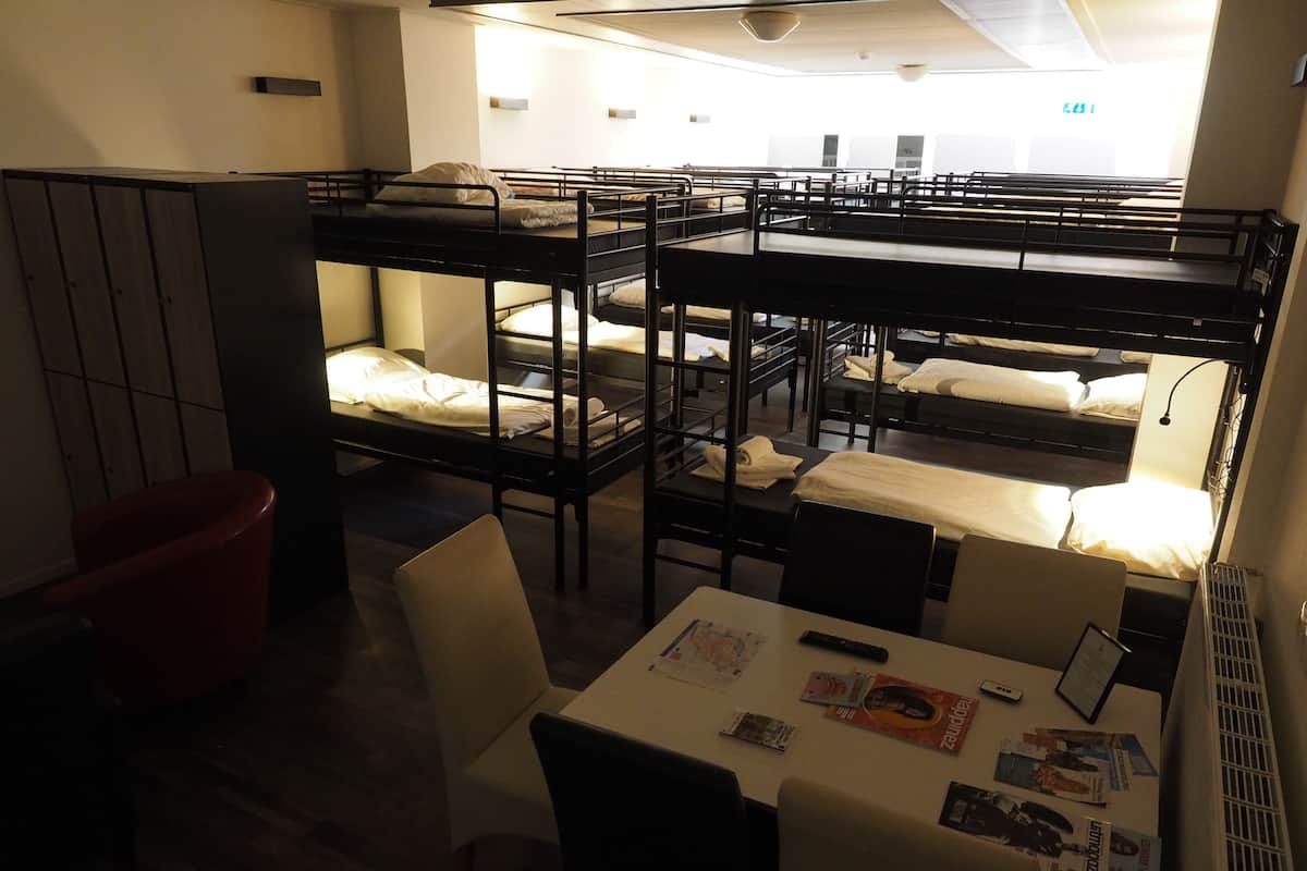 A dormitory room with bunk beds, a desk, and a chair.