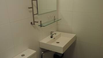 Une salle de bain avec des toilettes, un lavabo et un miroir.