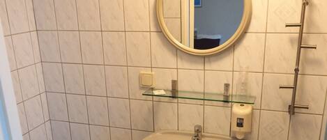 Un baño pequeño con inodoro, lavamanos y espejo.