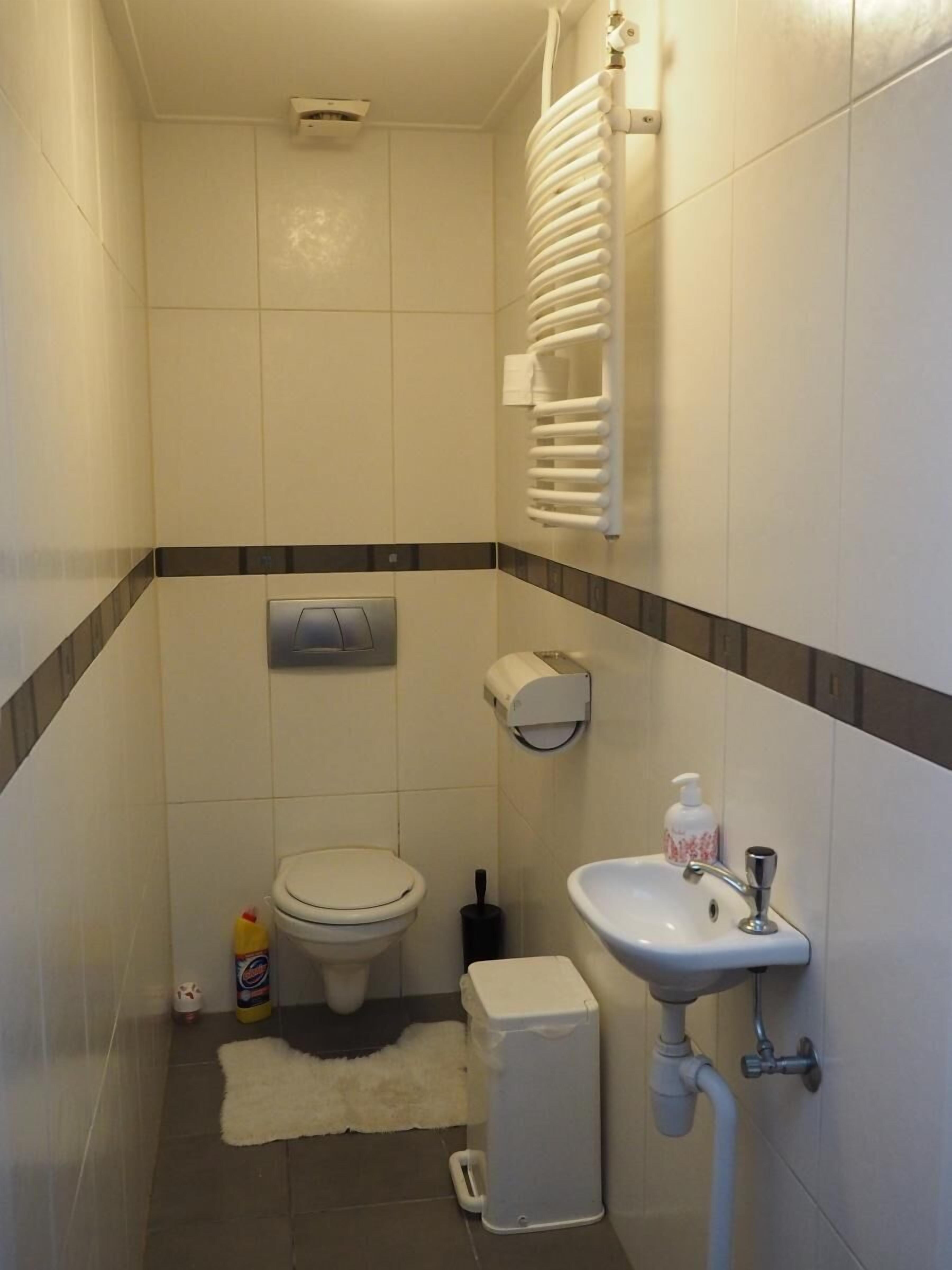 Un baño pequeño y limpio con inodoro, lavamanos y toallero.