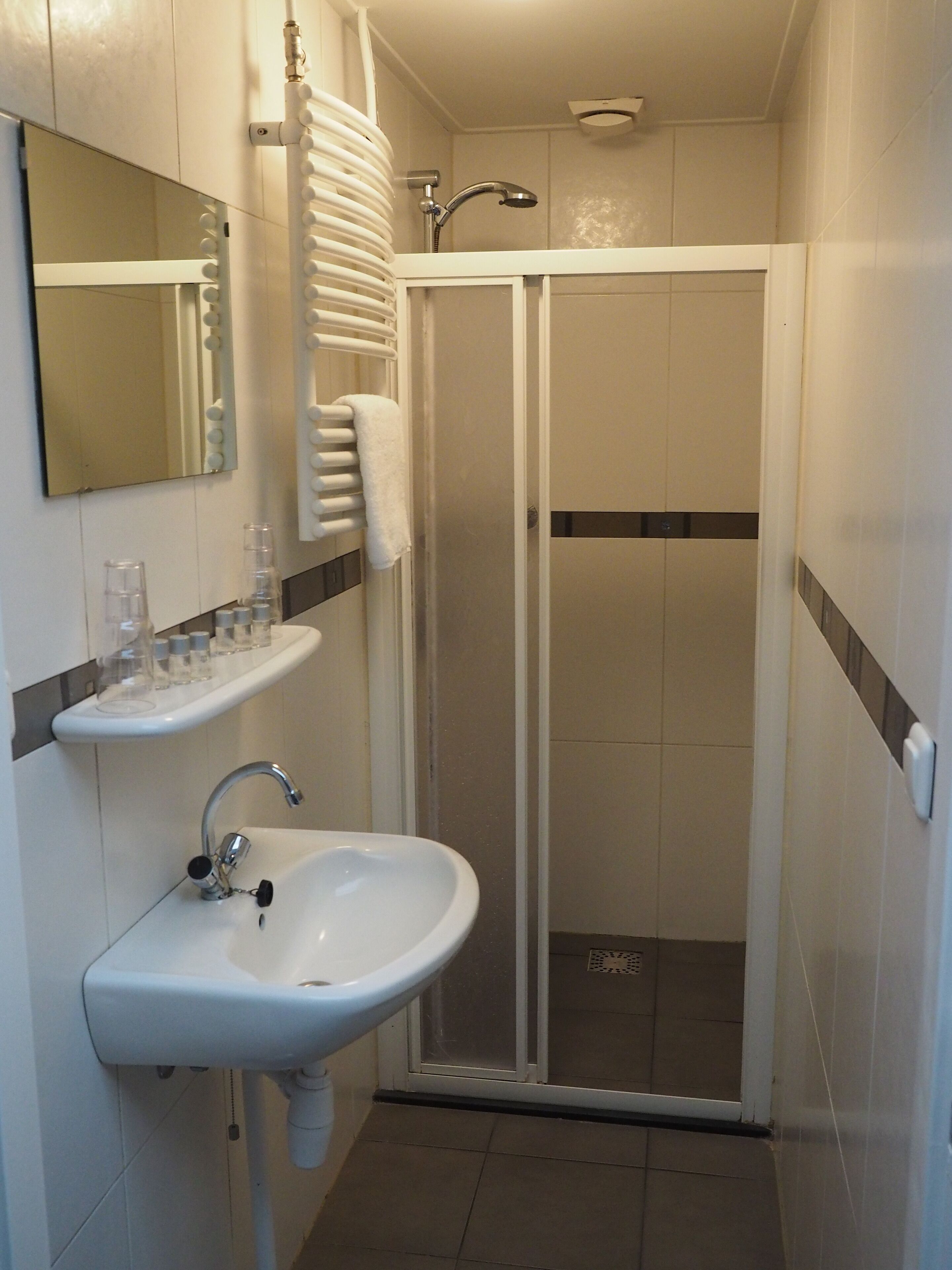 A bathroom with a white sink, mirror, and towel rack.