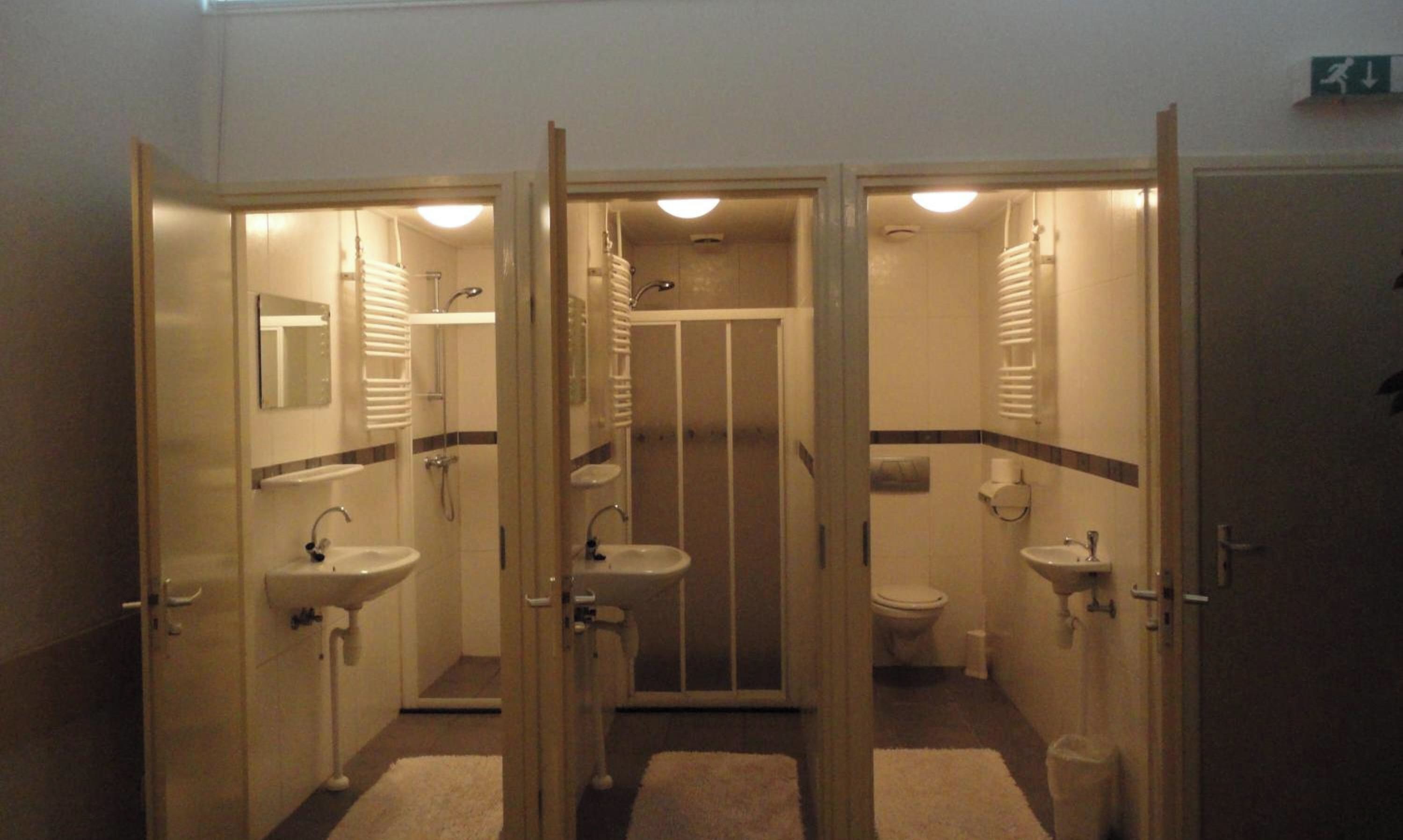 Un baño de hotel con tres cabinas separadas, cada una con lavamanos y espejo.