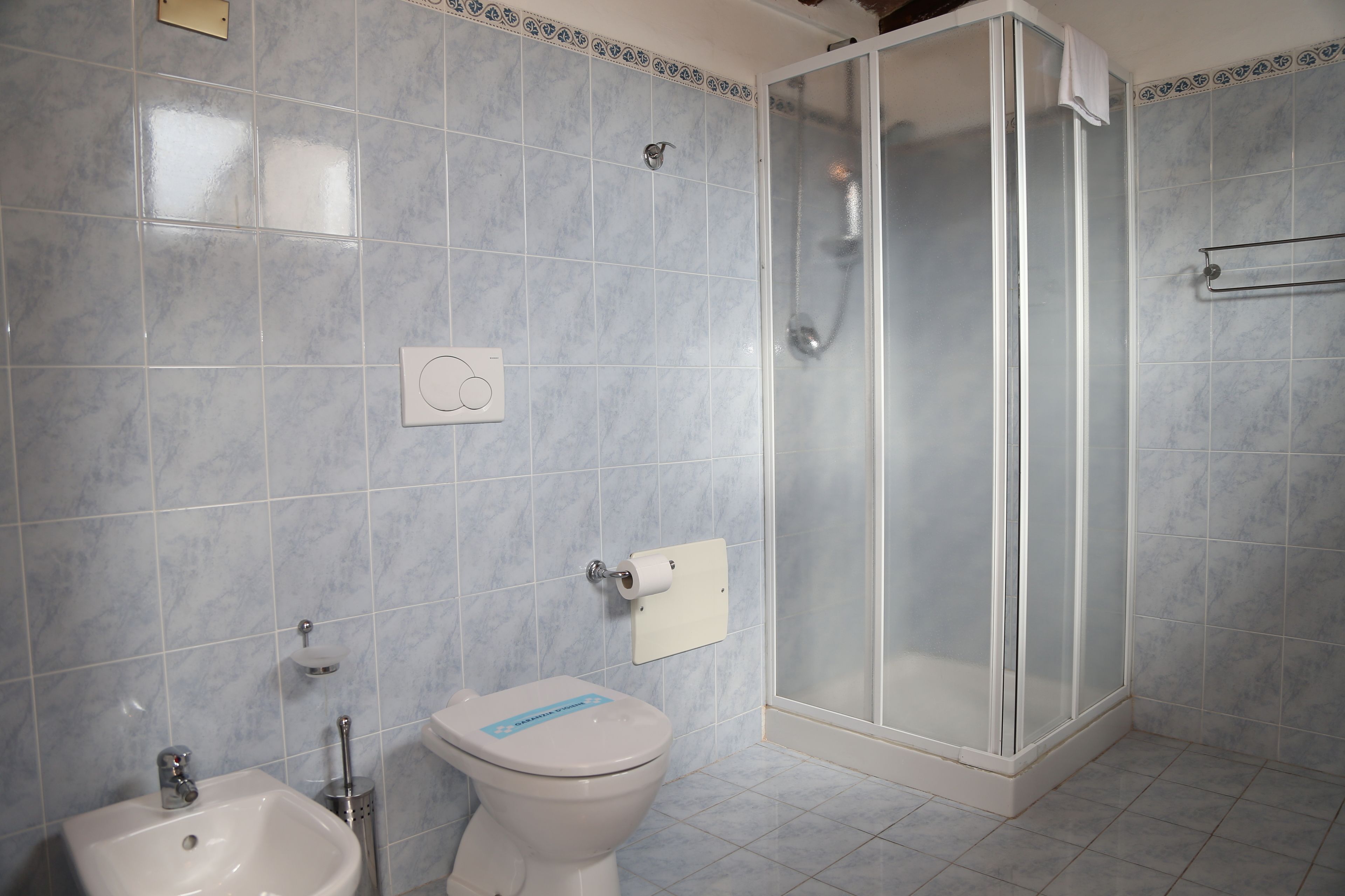 Casa de banho com sanita, bidé e cabine de duche de vidro.