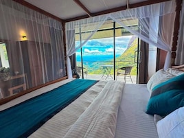 Un dormitorio con cama, vistas al exterior y una mesa con sillas.