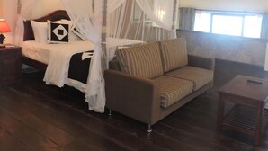Un dormitorio con cama a dosel, un sofá, una mesita y un ventilador de techo.
