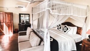 Un dormitorio con cama con dosel, sofá, televisor y ventilador de techo.