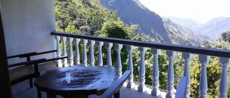 Un balcón con mesa y sillas, con vista a un paisaje montañoso.