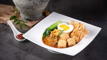 A square white plate with a noodle dish, egg, tofu, and vegetables.