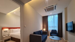 A hotel room with a bed, a sofa, a small table, and a TV. - Holiday Inn Express & Suites Johor Bahru by IHG (Johor Bahru)