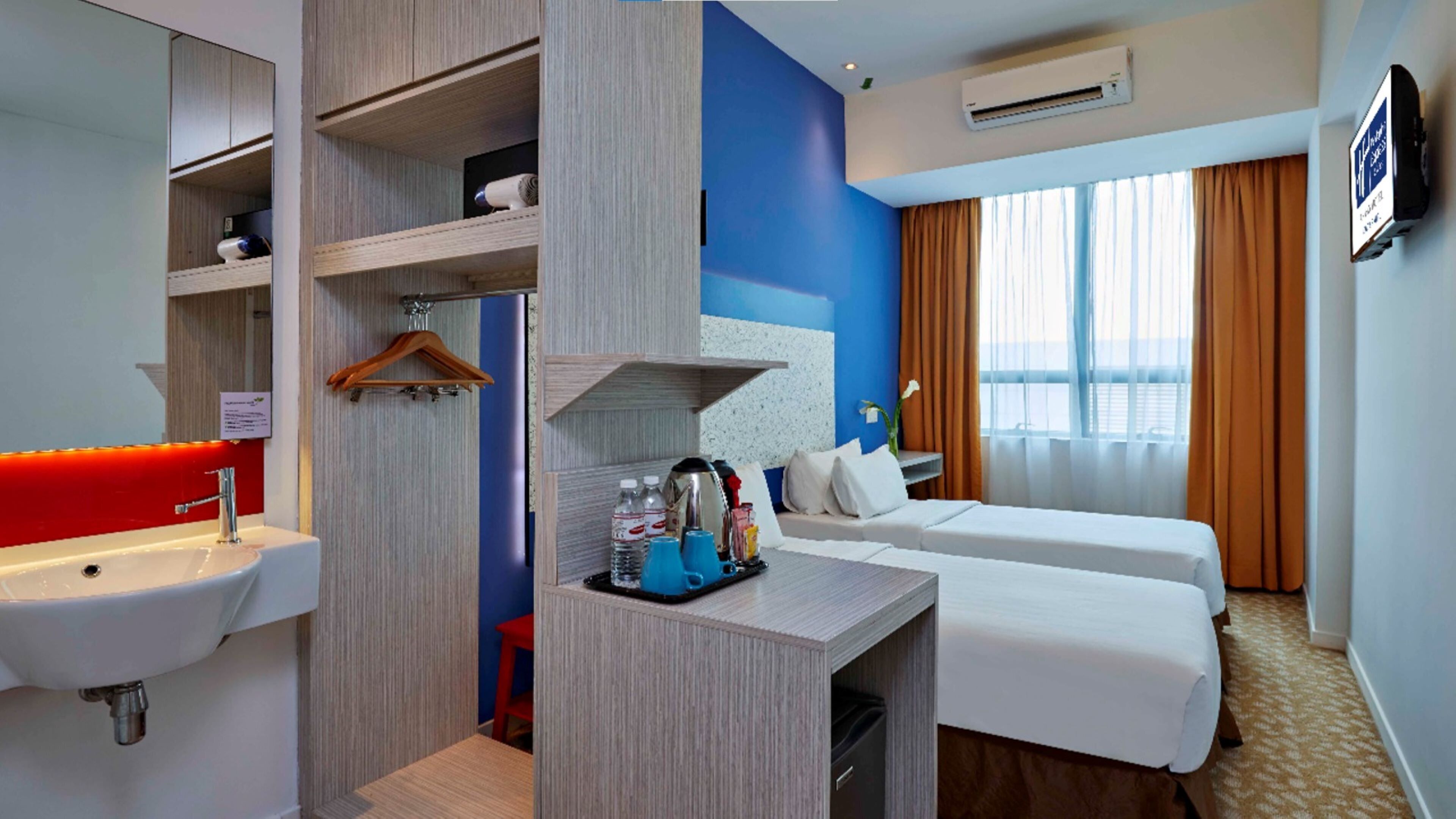 A hotel room with a bathroom, a desk with toiletries, a bed, and a TV.