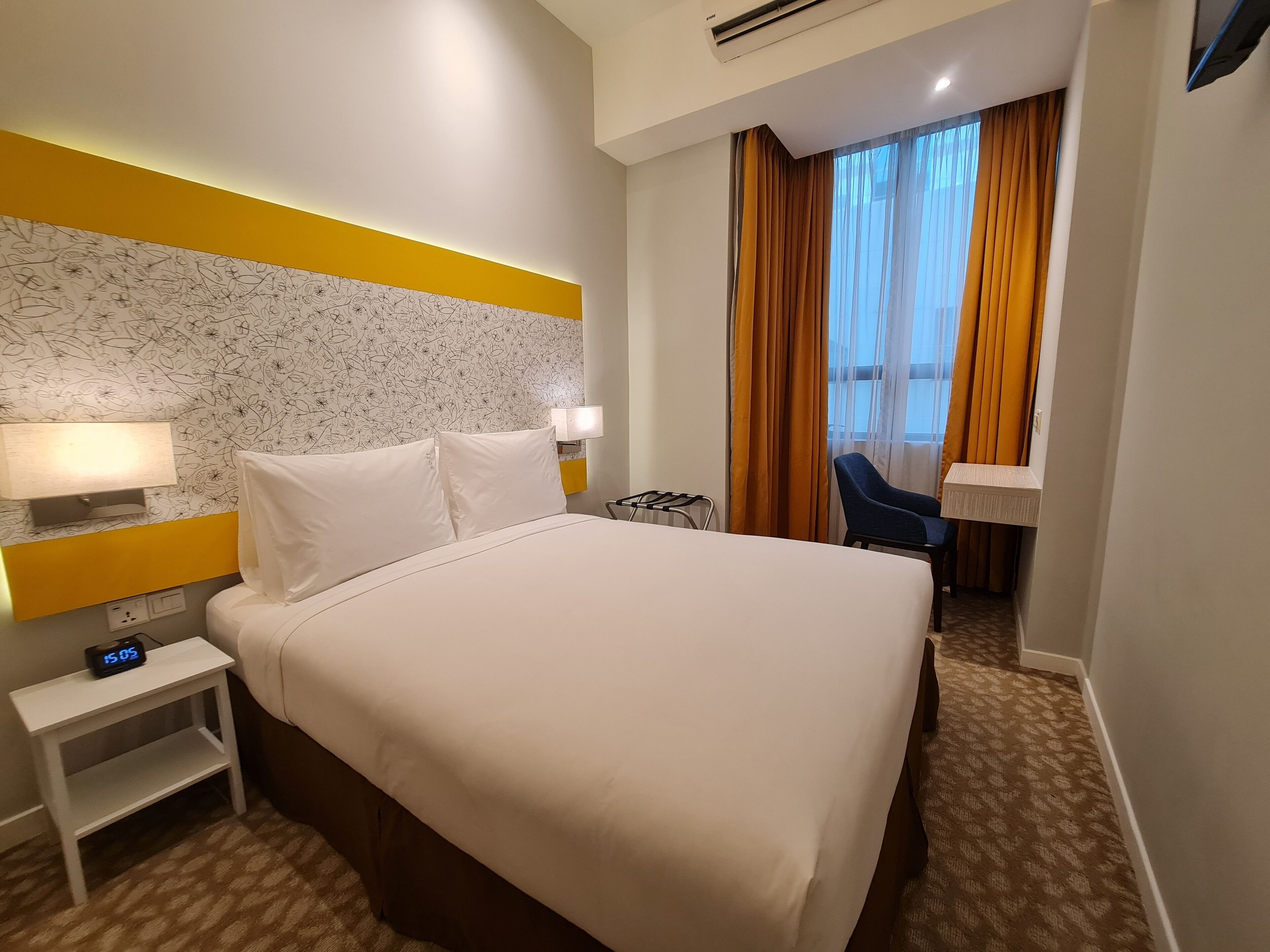 Une chambre d’hôtel avec un lit, une table de chevet, une lampe et une vue sur l’extérieur à travers les rideaux.