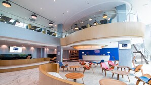 A spacious lobby with a curved reception desk, multiple seating areas, and a staircase leading to an upper level. - Holiday Inn Express & Suites Johor Bahru by IHG (Johor Bahru)